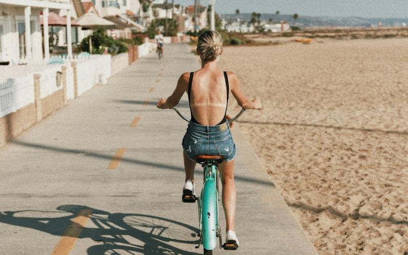 a person riding a bicycle on a road near a beach